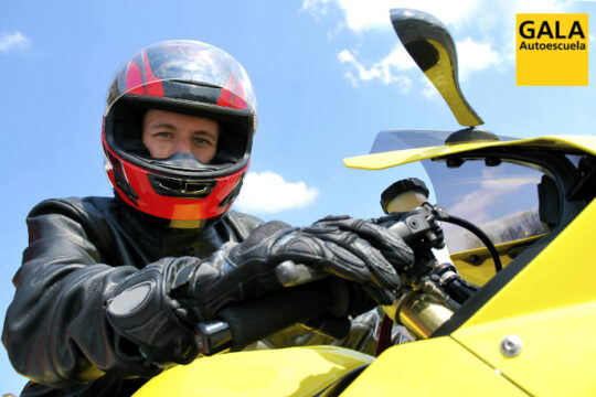 Motorista con moto amarilla y logo de Autoescuela Gala