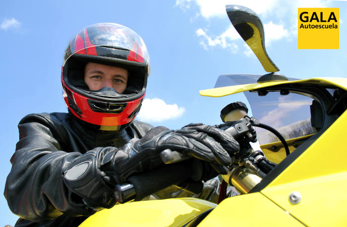 Motorista con moto amarilla y logo de Autoescuela Gala