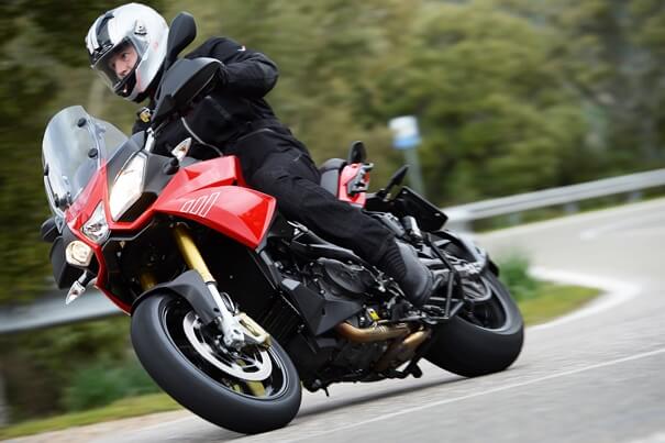 Artículo botas para viaje en moto: motorista equipado aborda una curva. | Piaggio Group