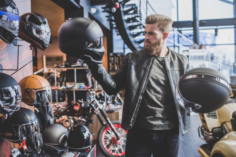 tienda de accesorios de moto en la que se encuentra un hombre joven escogiendo entre dos cascos de moto