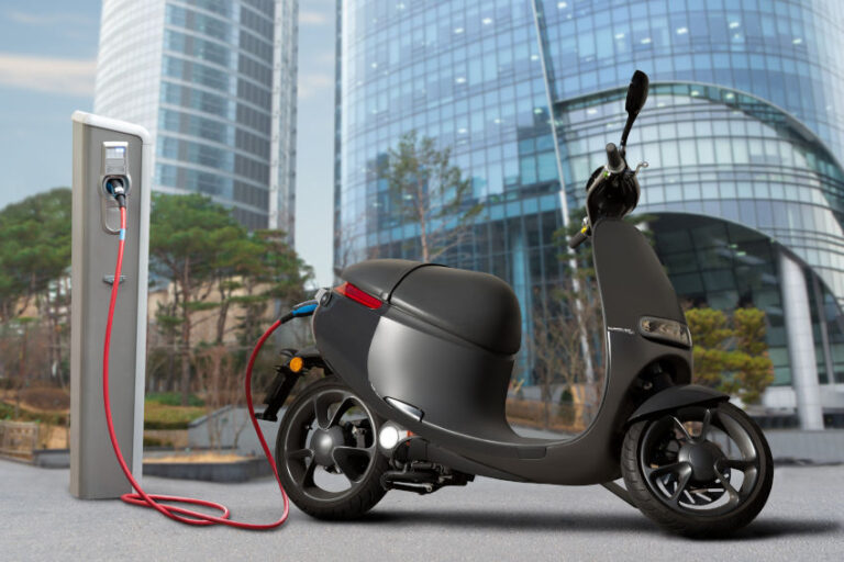 moto eléctrica tipo scooter conectada a un punto de carga de una ciudad