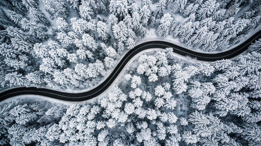 vista área de una carretera sinuosa con árboles nevados a los márgenes