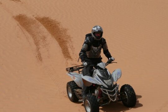 Hombre conduciendo un quad en el desierto