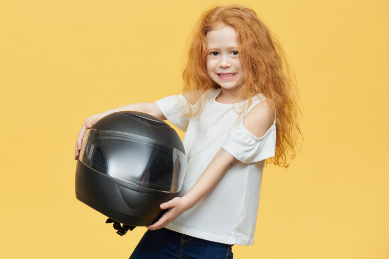 niña pelirroja sosteniendo un casco de moto integral