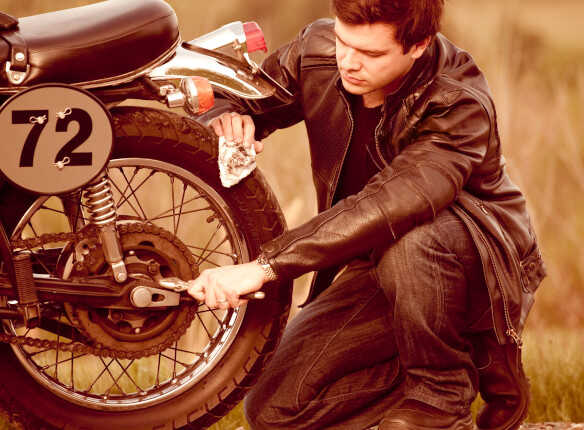 hombre apretando la rueda de una moto con una llave inglesa