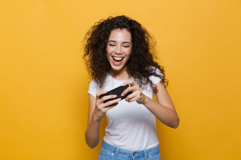 mujer joven sonriendo mientras juega con su móvil
