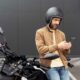 hombre apoyado sobre el lateral de su moto con el teléfono móvil en las manos