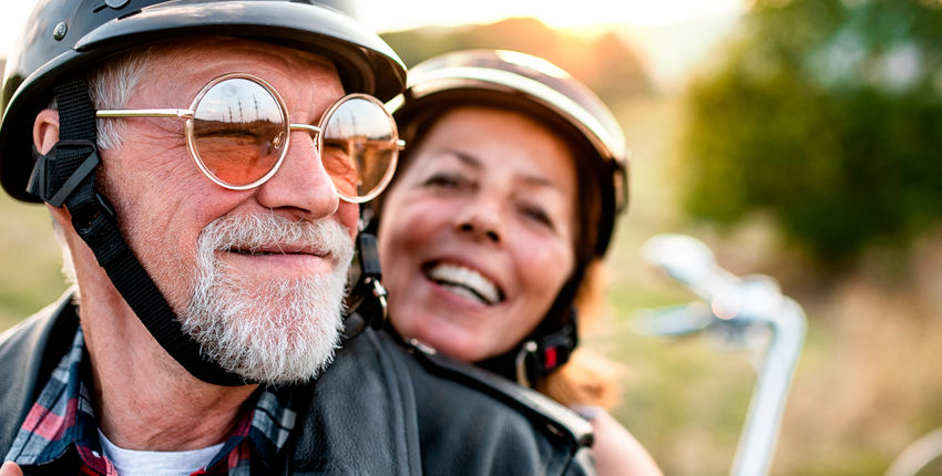 dos personas mayores sonriendo mientras montan en moto