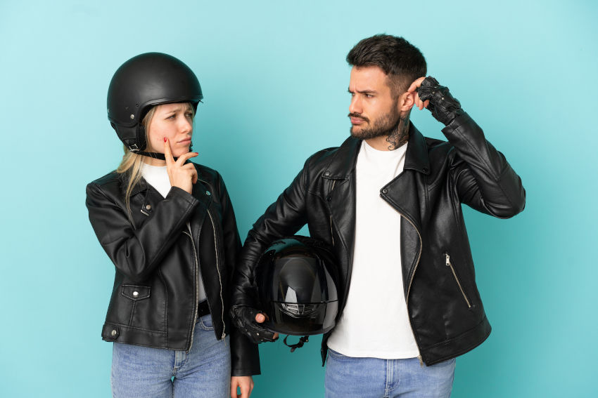 pareja con gesto de duda vestida con chaqueta de cuero y casco de moto