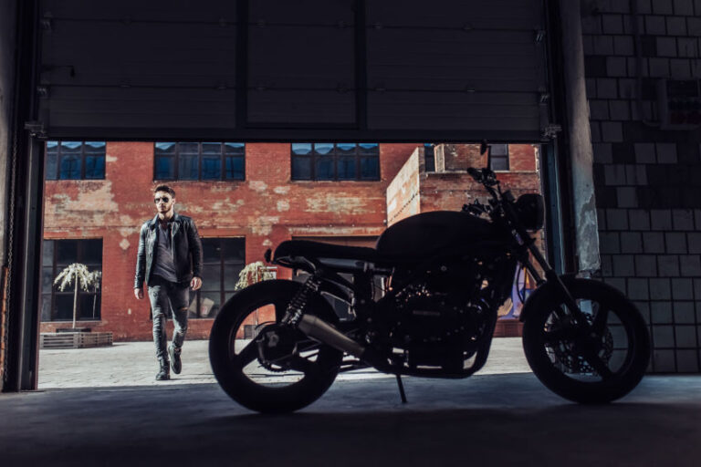 Motero entrando en un garaje donde se encuentra una moto negra de estilo Cafe racer