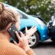 mujer rubia de espaldas haciendo una llamada de teléfono mientras observa dos coches que han chocado